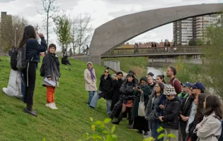 Grupo de gente atiende a una mujer que les habla en un parque