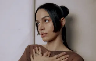 chica posa con las manos cruzadas sobre el pecho