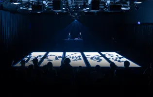 Unos grandes paneles con iconografía japonesa en el suelo están iluminados con una luz blanca en una sala oscura