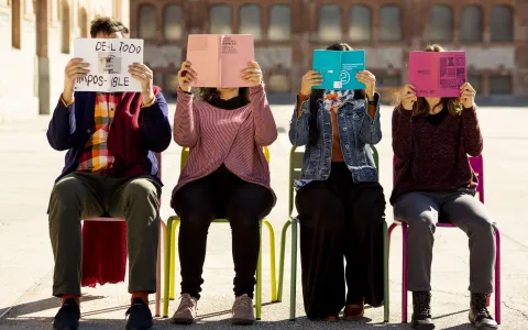 cuatro personas están sentadas y se tapan la cara con un papel