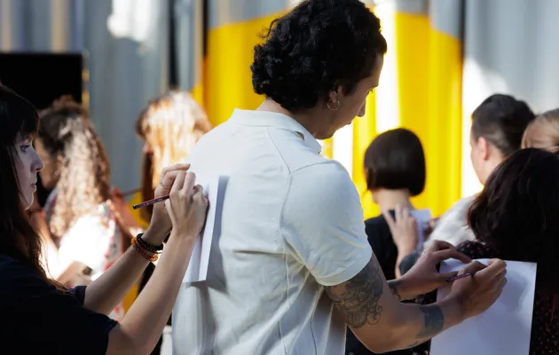 Alguien escribe apoyando el papel en las espalda de un chico