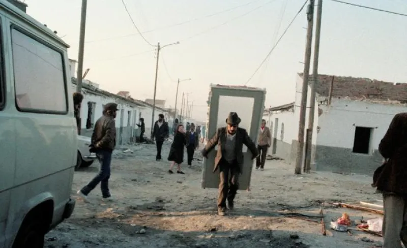 Un vecino acarrea una puerta a la espalda por un descampado