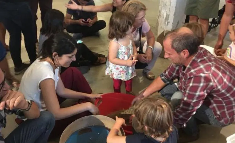 Adultos y niños comparten una tarea sentados en el suelo