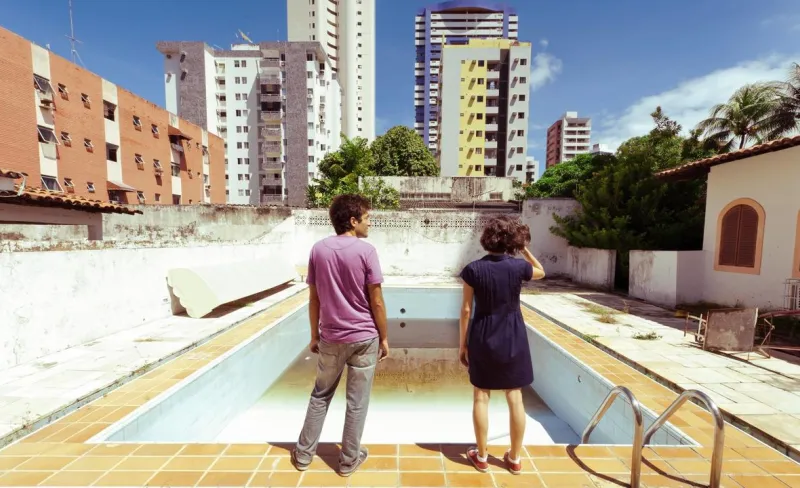 Personas observan una piscina vacía con rascacielos de fondo