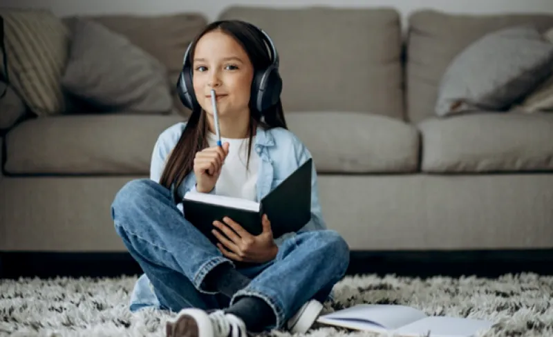 Niña con cascos escribe en un cuaderno