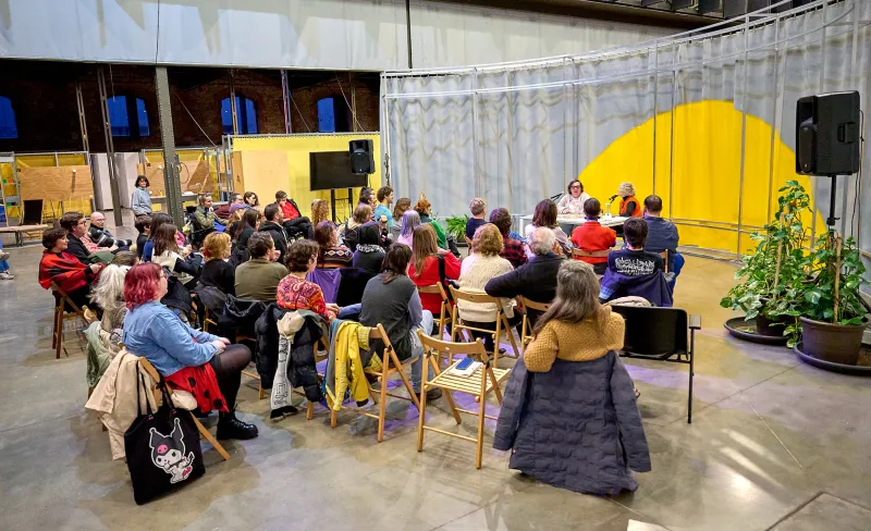 Personas sentadas escuchan a dos ponentes