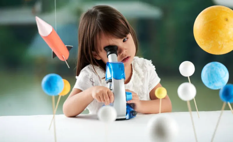 Niña mira por un microscopio