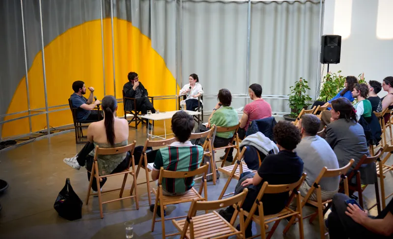 Varias personas atienden a una charla entre tres mujeres