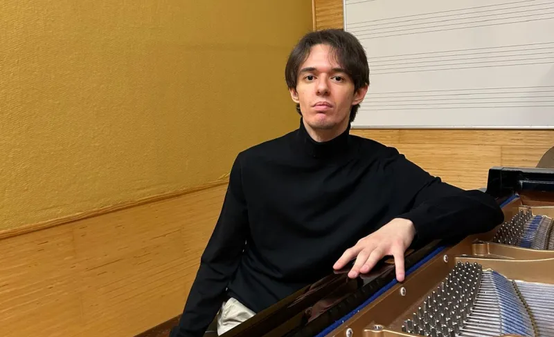 Chico posa apoyado en una mesa de mezclas para producción musical