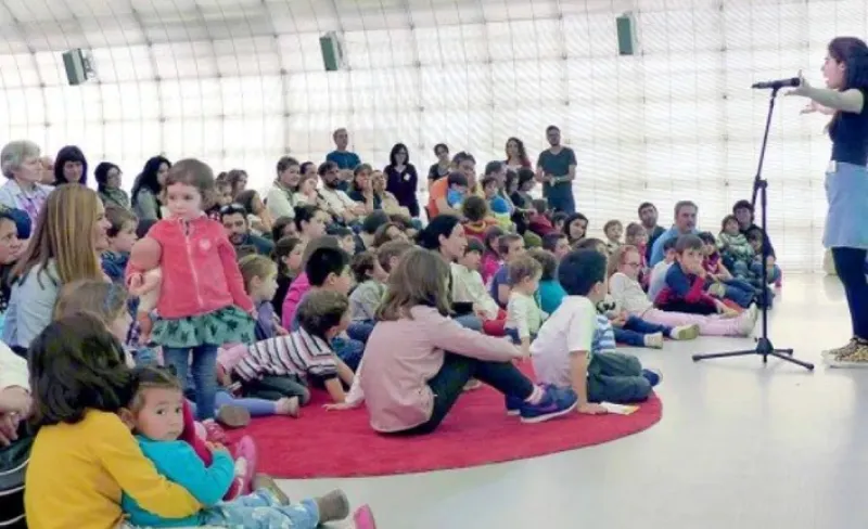 Niños sentados en el suelo atendiendo a un cuentacuentos