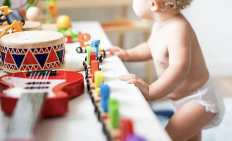 un bebé observa una mesa llena de instrumentos infantiles y juguetes