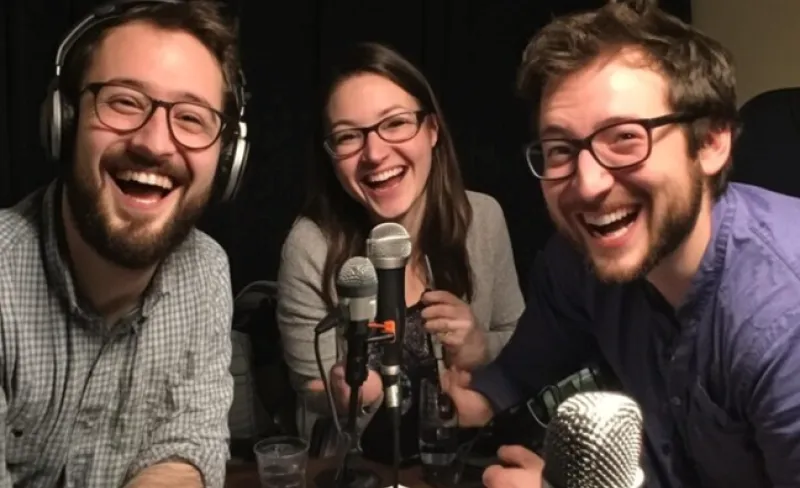 dos chicos y una chica ríen frente a un micrófono
