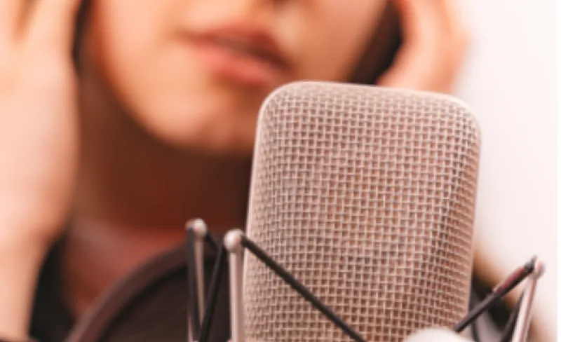 Una joven locutora con cascos delante de un micrófono