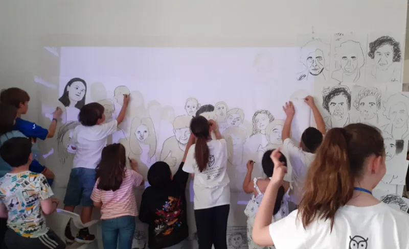 Grupo de niños pintan un panel de papel en una pared