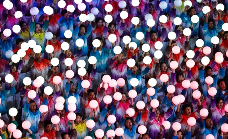 Plano cenital de gente vestida de colores sujetando unas bolas de luz blanc