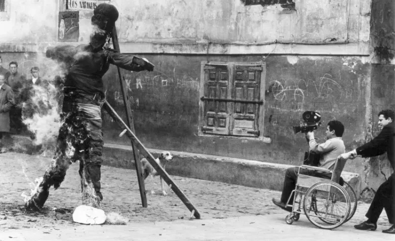 Una persona en una silla de ruedas filma la quema de un muñeco en la calle