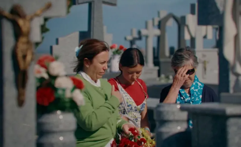 tres mujeres frente a una lápida en un cementerio