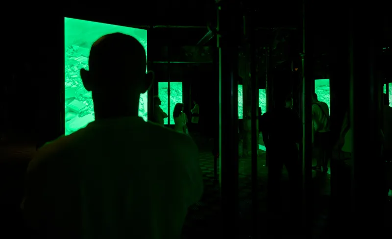 Siluetas de gente a oscuras mirando una pantalla verde