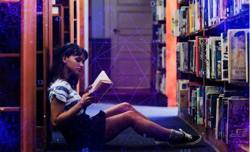 una adolescente lee sentada en el pasillo de una biblioteca