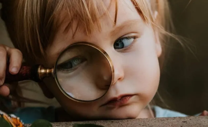 Un niño mira por una lupa