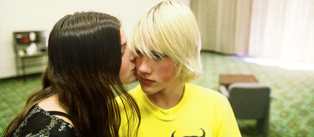 Chica morena besa en la mejilla a chico adolescente rubio