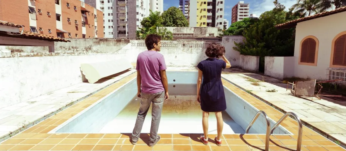Personas observan una piscina vacía con rascacielos de fondo