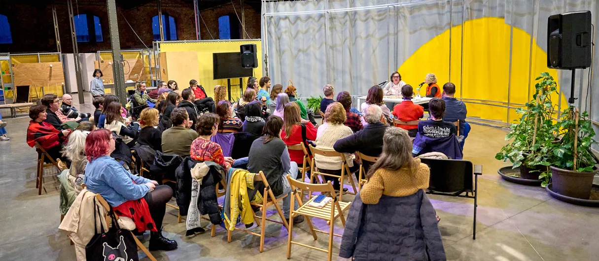 Personas sentadas escuchan a dos ponentes