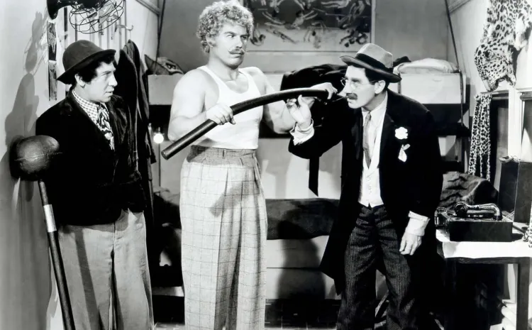 Hombre con bigote y sobrero, Groucho Marx, mira incrédulo a un forzudo que dobla una barra