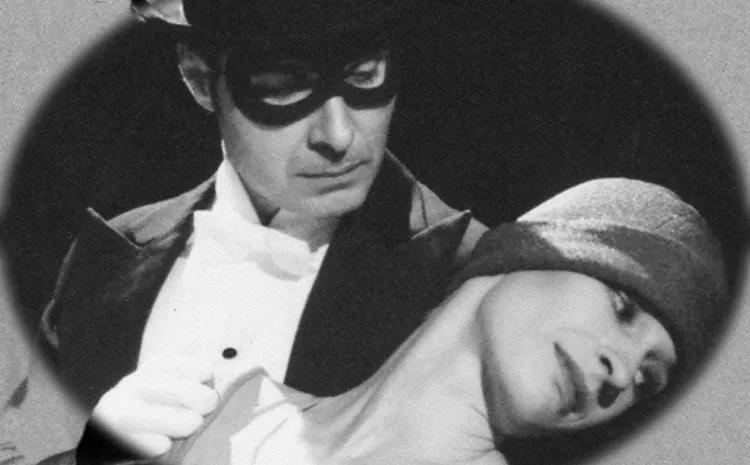 Hombre con antifaz y sombrero sujeta y mira a una mujer con pañuelo en la cabeza