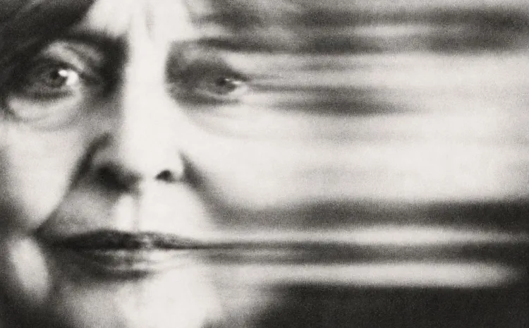 Fotografía en blanco y negro del rostro de una mujer adulta con un haz borroso al lado