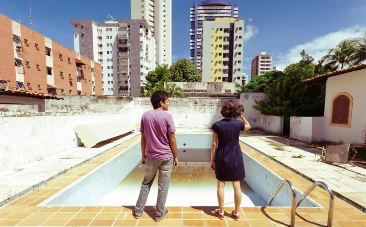 Personas observan una piscina vacía con rascacielos de fondo