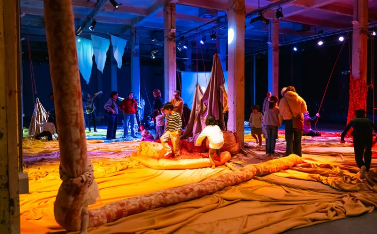 Niños y niñas jugando con cojines y otras piezas de tela