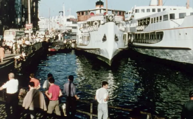 Gente observa un barco atracado en un puerto 