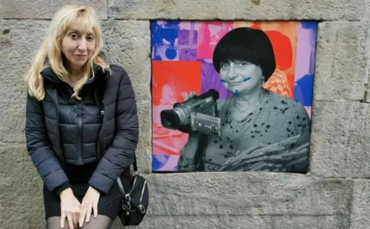Una mujer posa junto a un cartel de otra mujer vandalizado