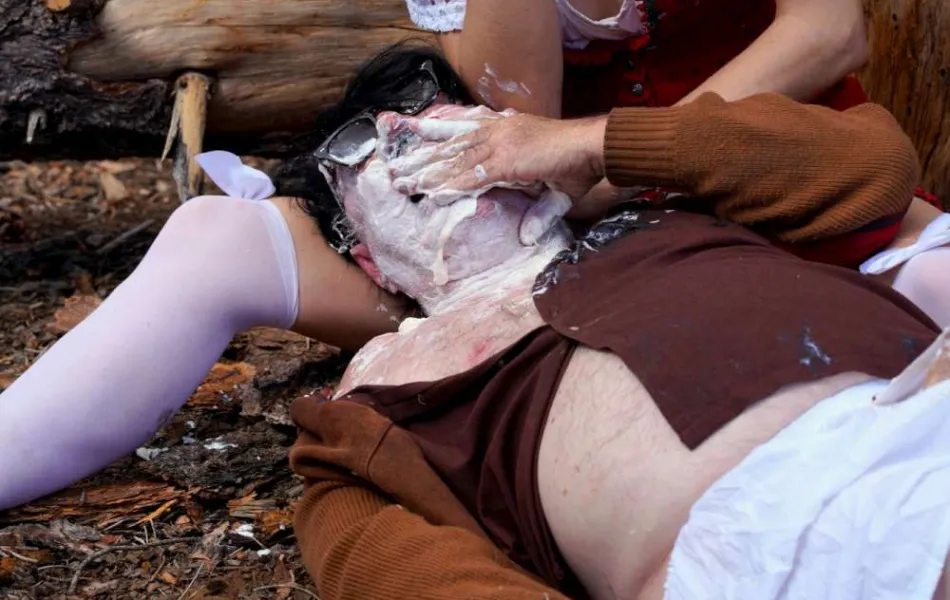 Hombre sobre regazo de mujer ambos con la cara llena de merengue