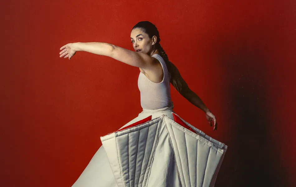Una mujer en pose de baile con un vestido blanco con una falda abultada