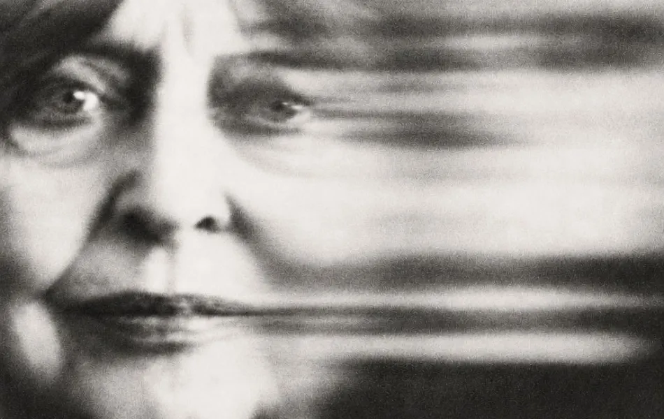 Fotografía en blanco y negro del rostro de una mujer adulta con un haz borroso al lado