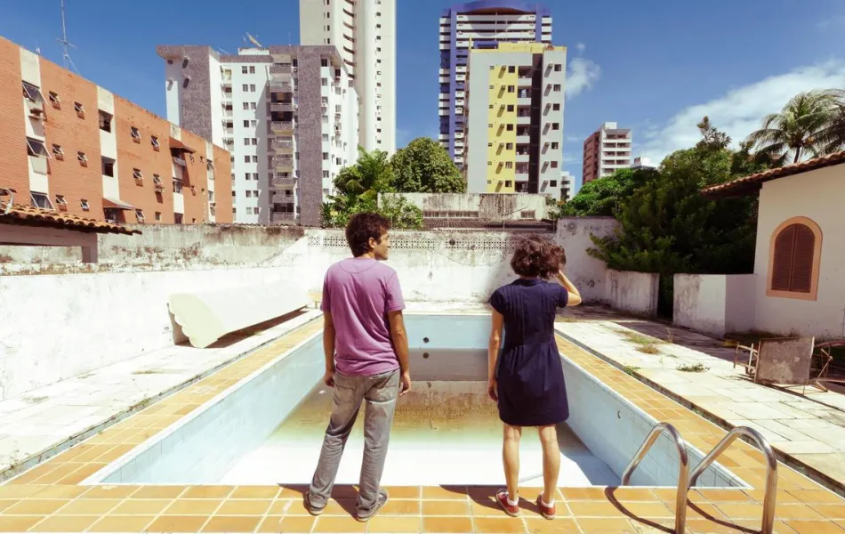 Personas observan una piscina vacía con rascacielos de fondo