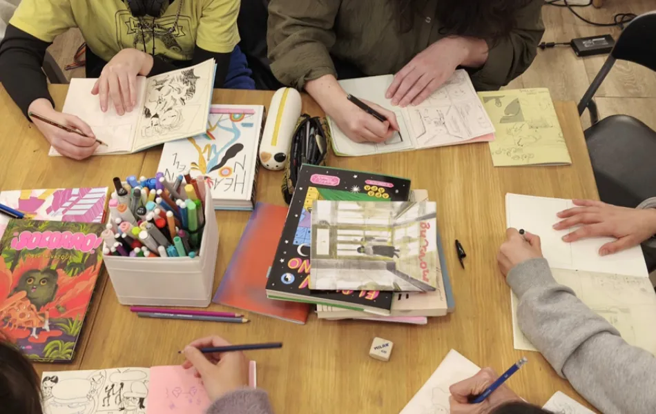 materiales de dibujo sobre una mesa y manos que lo manejan