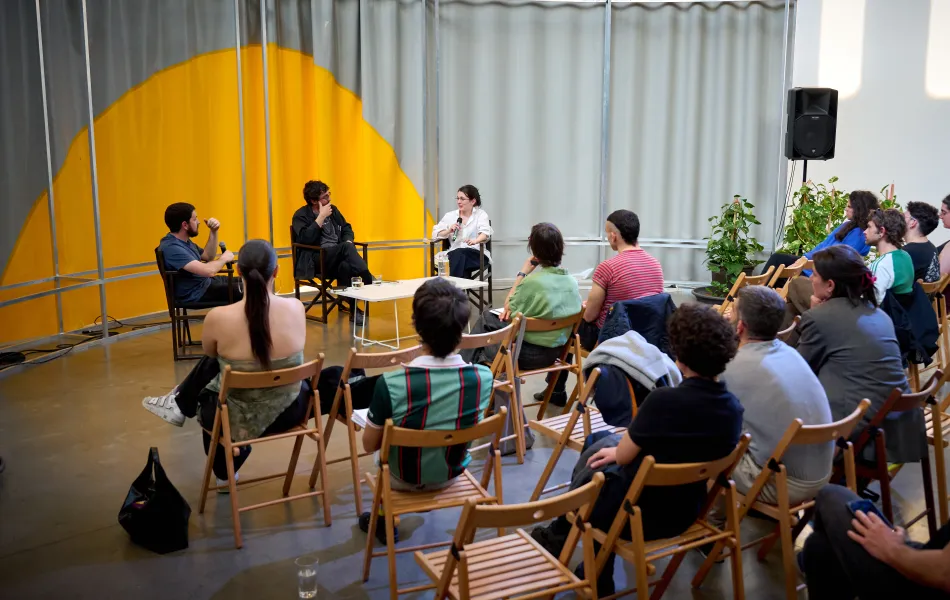 Varias personas atienden a una charla entre tres mujeres