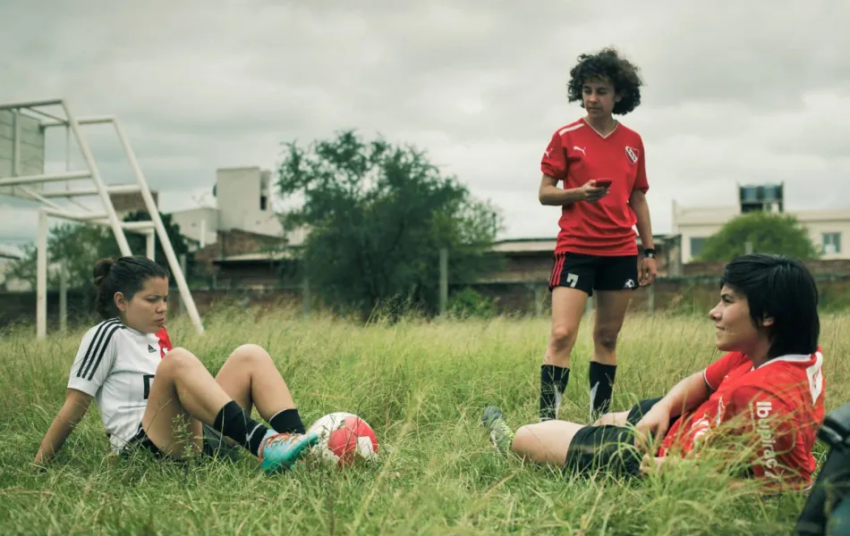Tres adolescentes descansan en un campo de fútbol