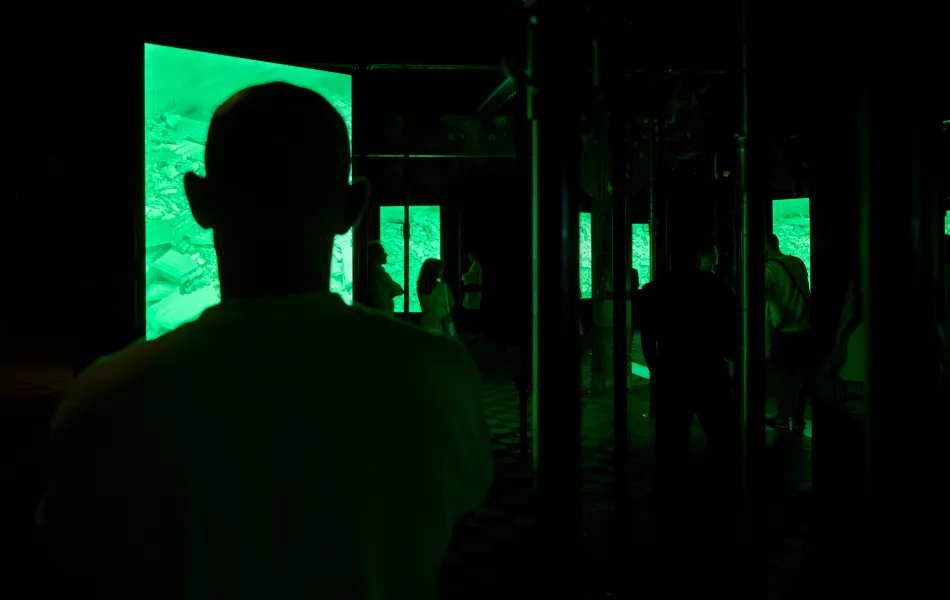 Siluetas de gente a oscuras mirando una pantalla verde
