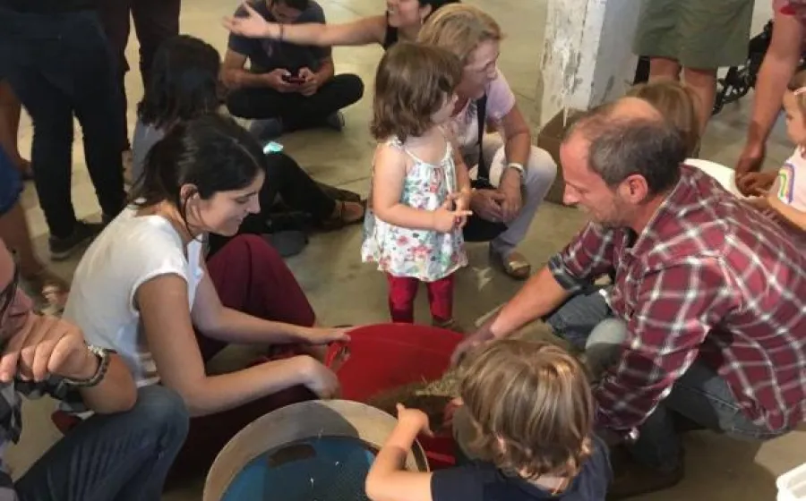 Adultos y niños comparten una tarea sentados en el suelo