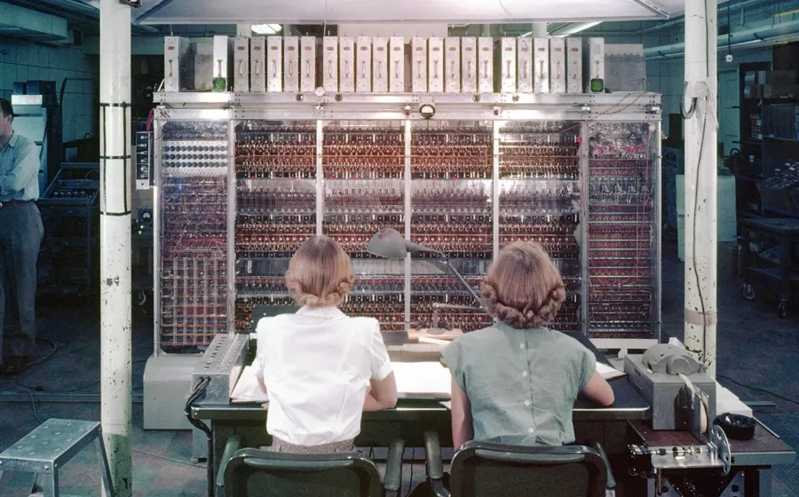 dos mujeres sentadas de espaldas delante de un panel con conexiones