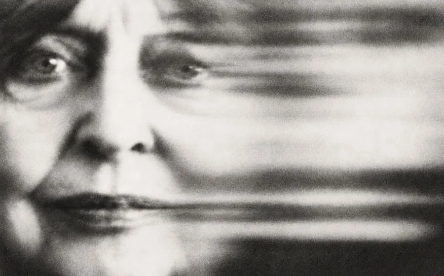 Fotografía en blanco y negro del rostro de una mujer adulta con un haz borroso al lado