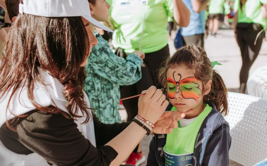 Maquilladora pinta la cara de una niña como una mariposa