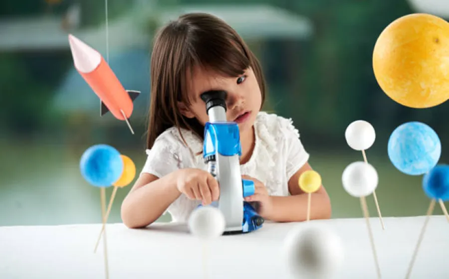 Niña mirando por un microscopio