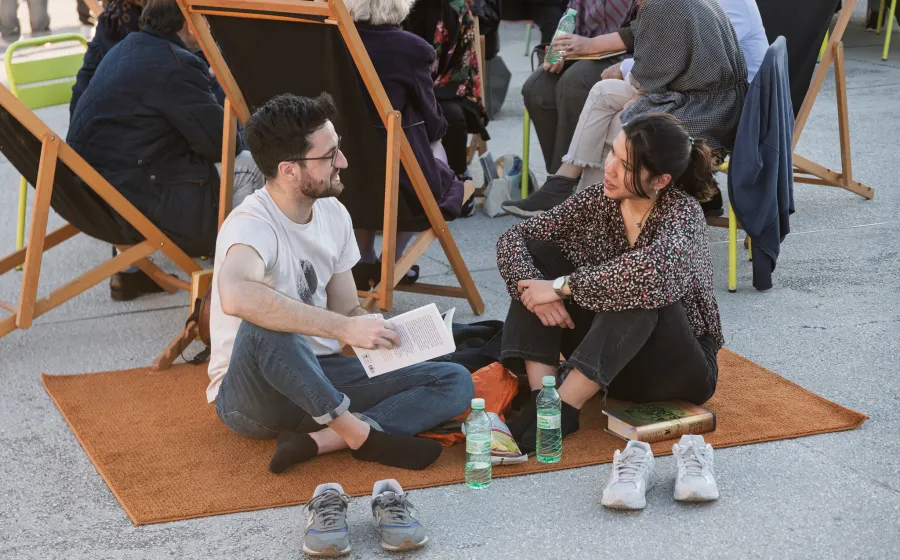 Chica y chico se miran con libros en la mano sentados en el suelo