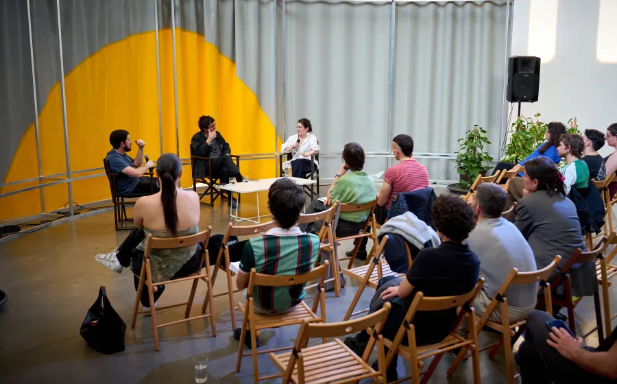 Varias personas atienden a una charla entre tres mujeres