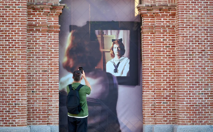 Un hombre fotografía una foto en formato grande que ocupa un vano en una pared de ladrillo